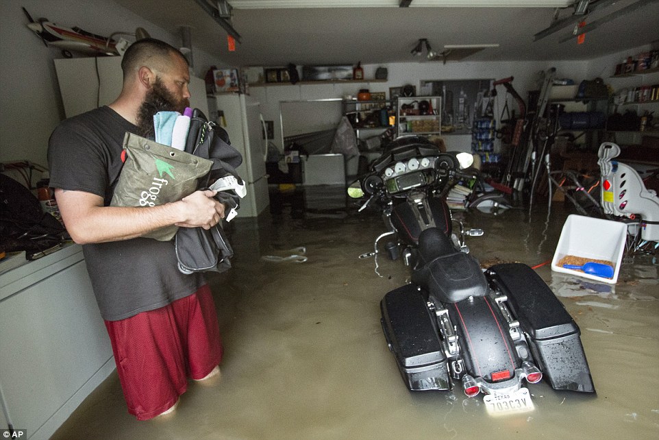 334CDAB500000578-0-A_man_holds_his_belongings_as_he_evaluates_his_submerged_motorcy-a-67_1461033537684.jpg